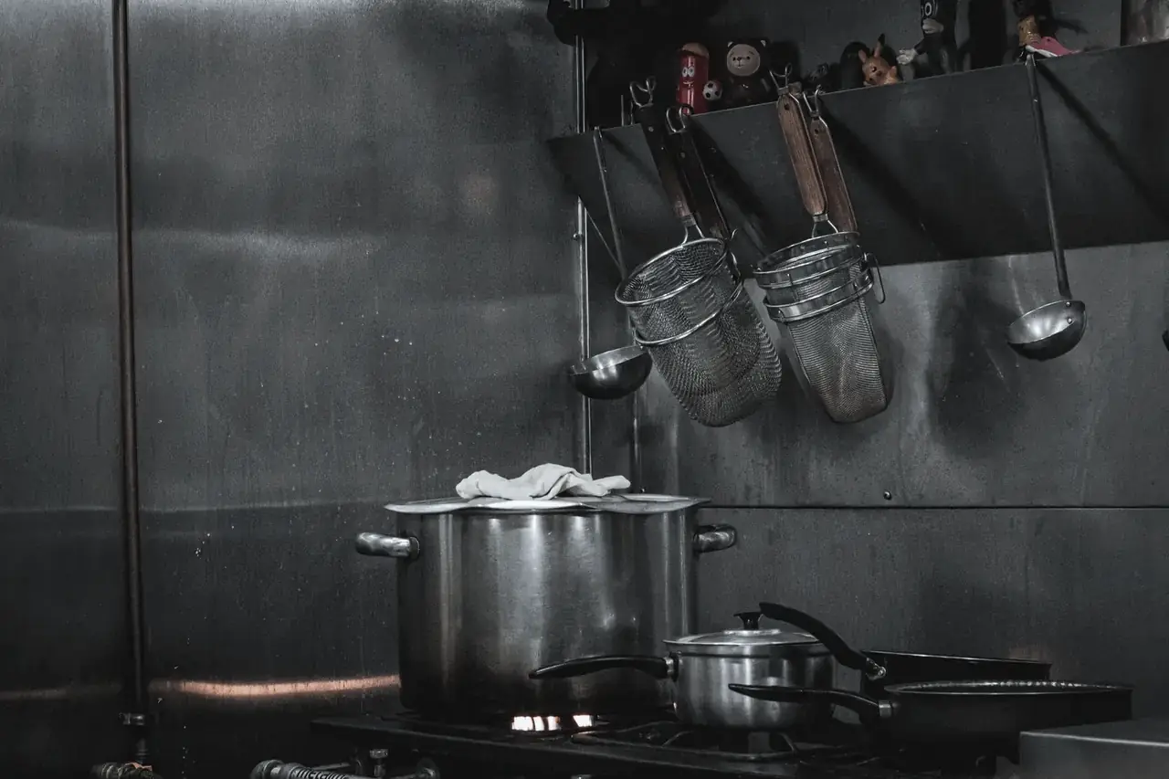 Commercial kitchen fabricated in stainless steel with pots and rails